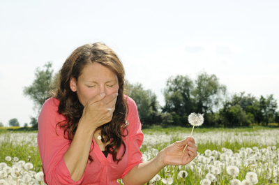 Frau niest auf einer Blumenwiese